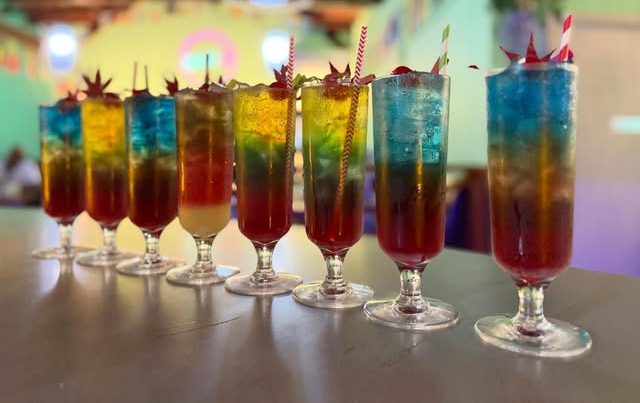 A row of layered rainbow mocktails on the bar at Zens